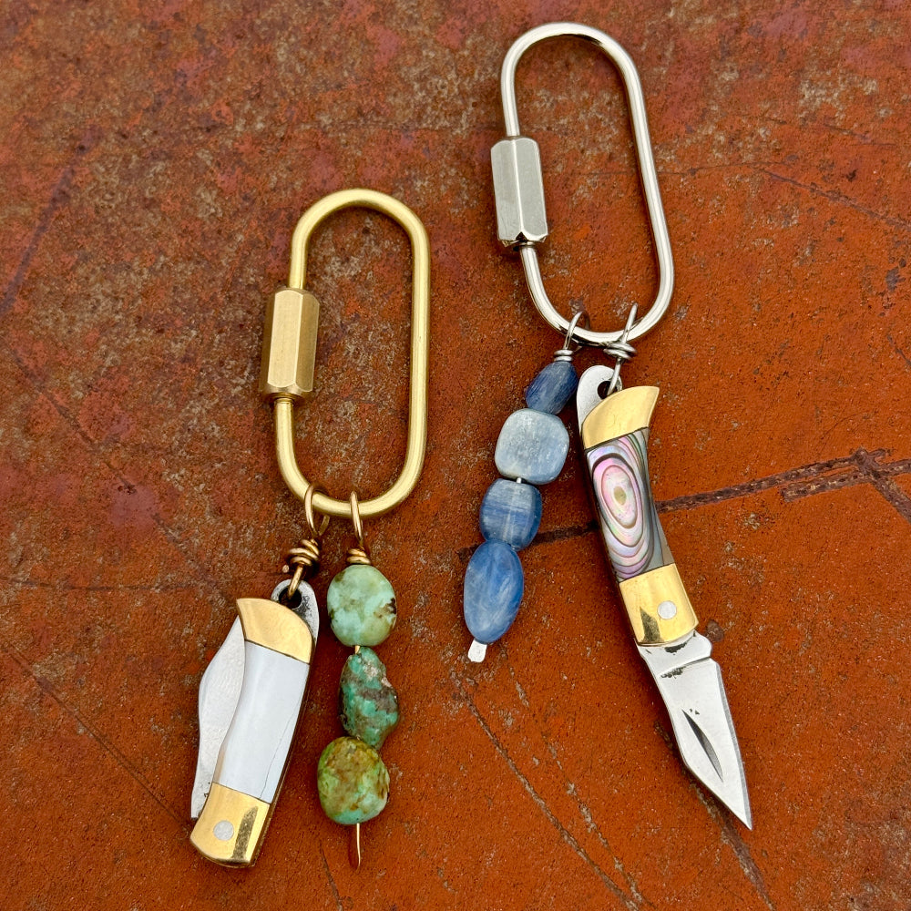 Two keychain purse charms with decorative elements on a textured brown surface