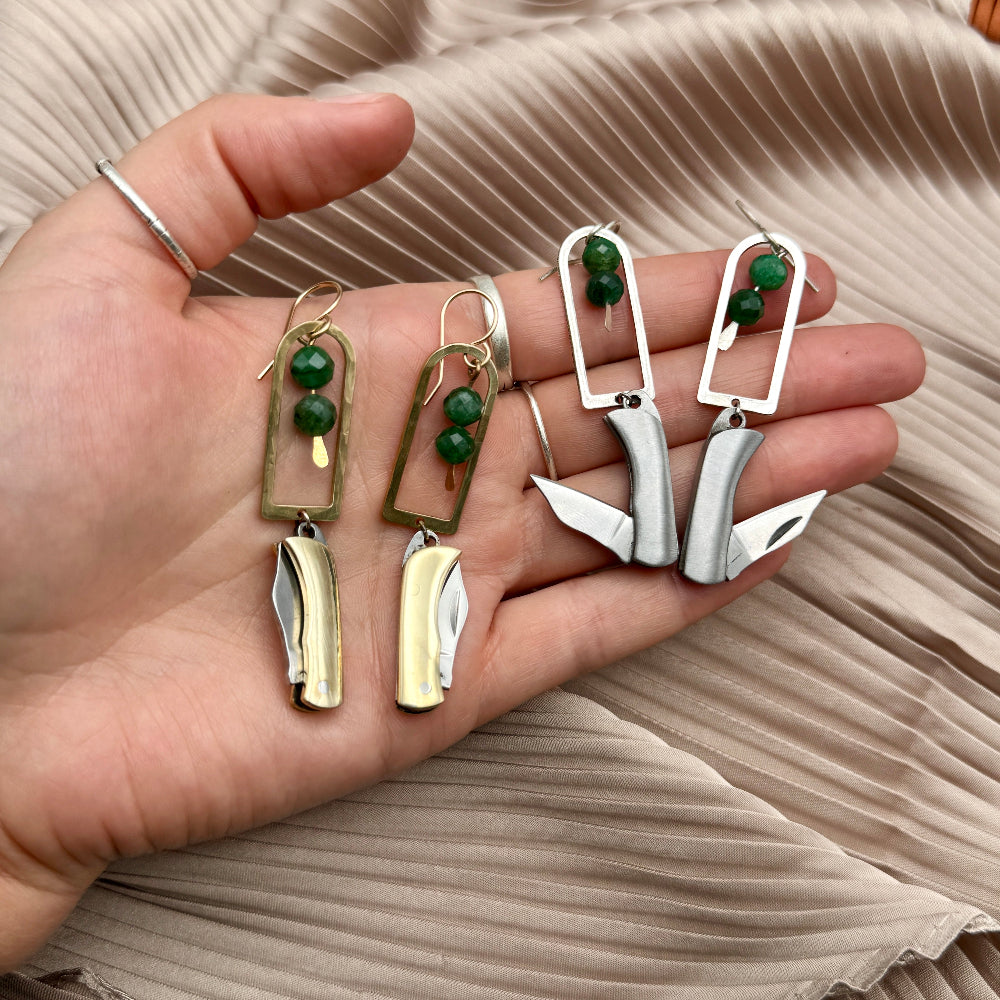 Silver and Gold Metal Billie Mini Pocket Knife dangling from rounded top frame with two faceted emerald beads hanging from ear wire