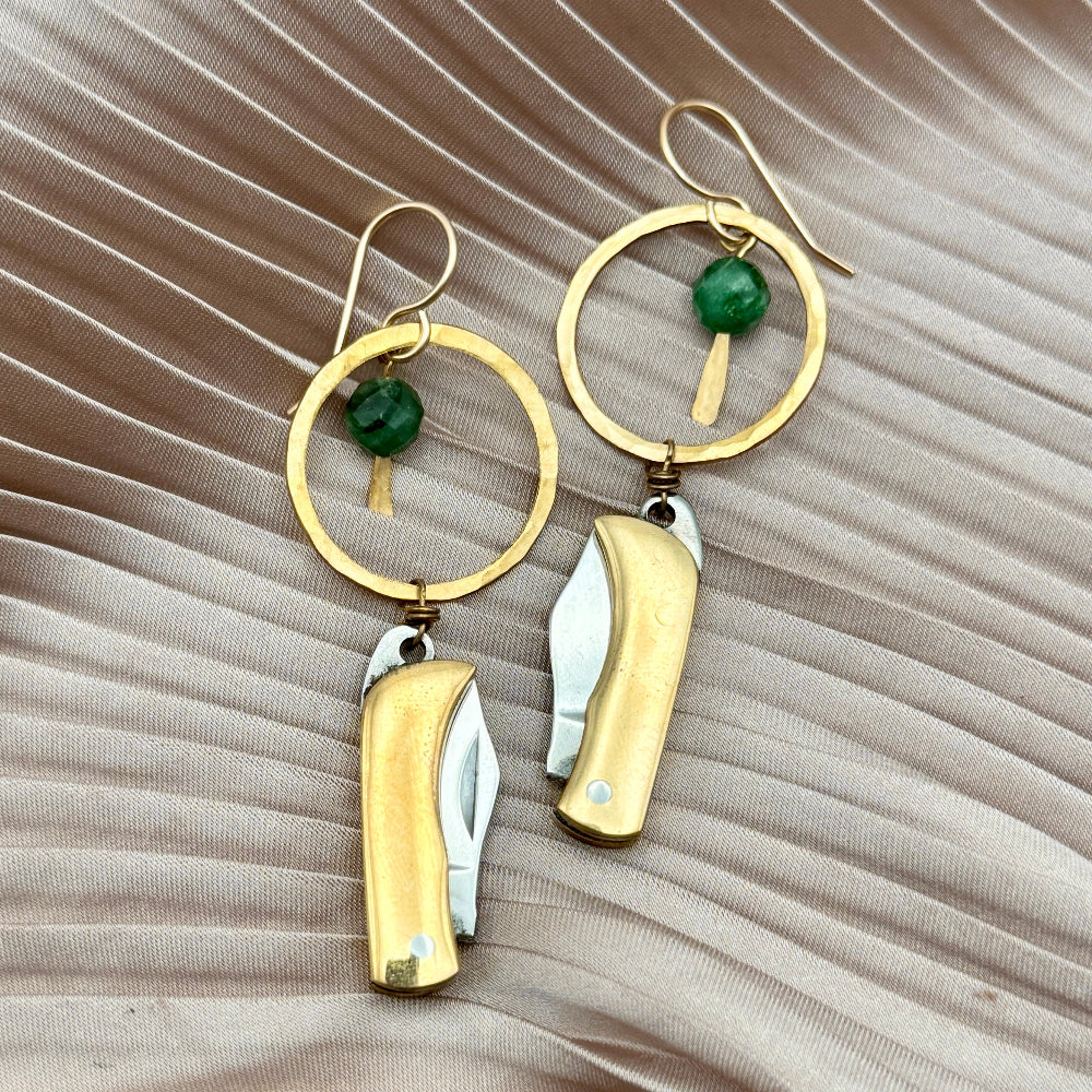 Gold Metal Billie Knives hanging from circle pendant with emerald bead from ear wire