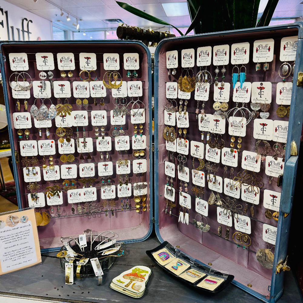 Open jewelry case displaying various pairs of handmade earrings.