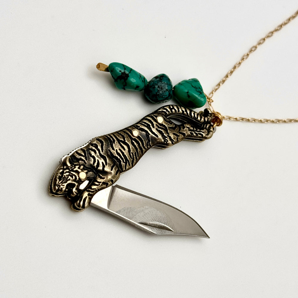 Necklace with tiger pocketknife blade pendant on a white background with the blade partially opened