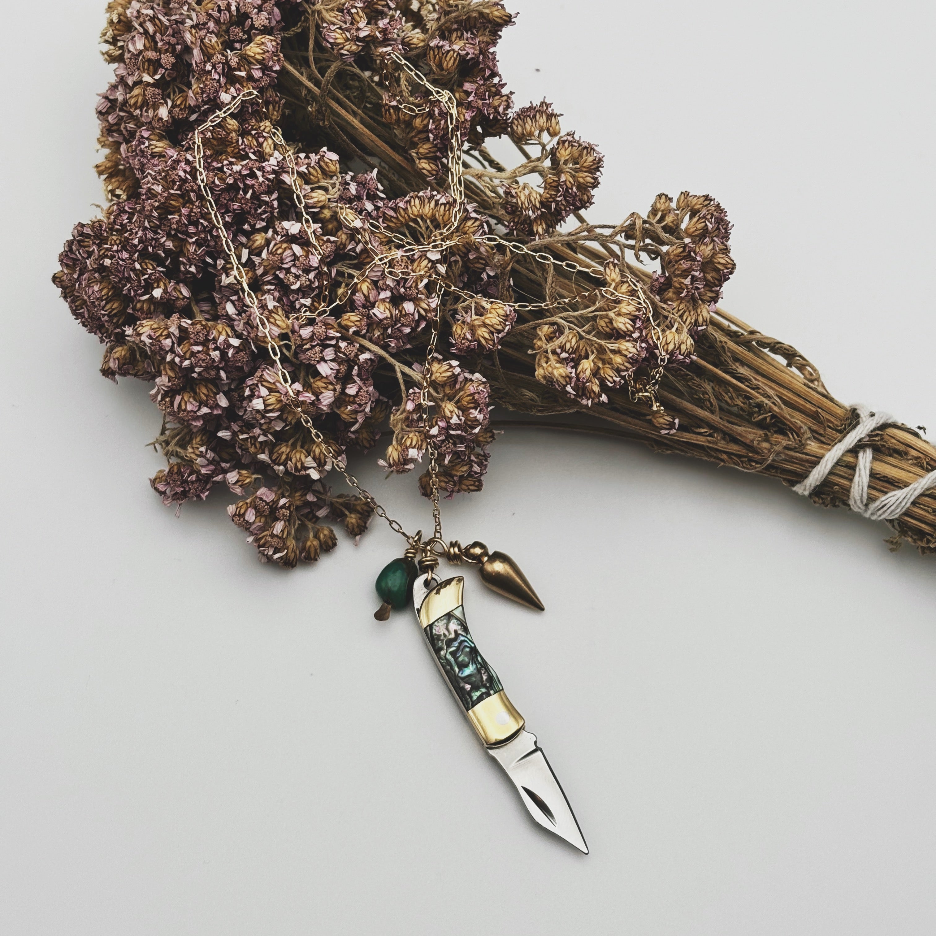 Abalone inlay and gold handle miniature pocketknife hanging with a turquoise stone and mini bullet