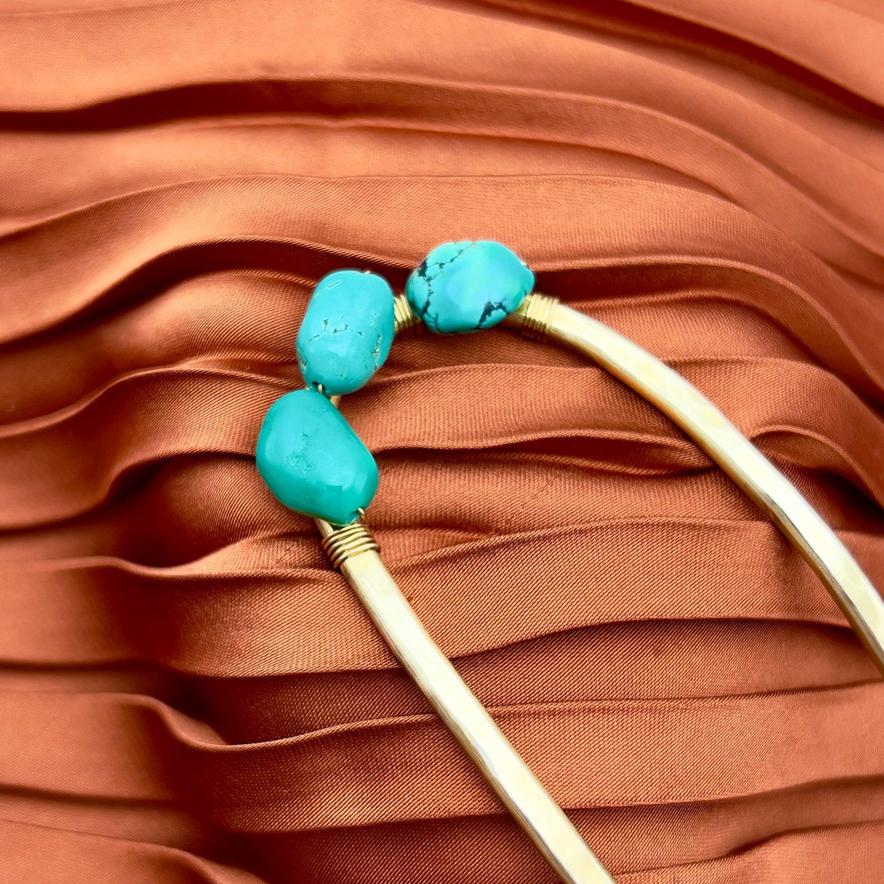 Close-up of Fluff Hardware’s Turquoise Hair Fork, featuring three turquoise stones on copper-brown fabric—perfect inspiration for styling or pairing with brass hair forks adorned with turquoise beads.