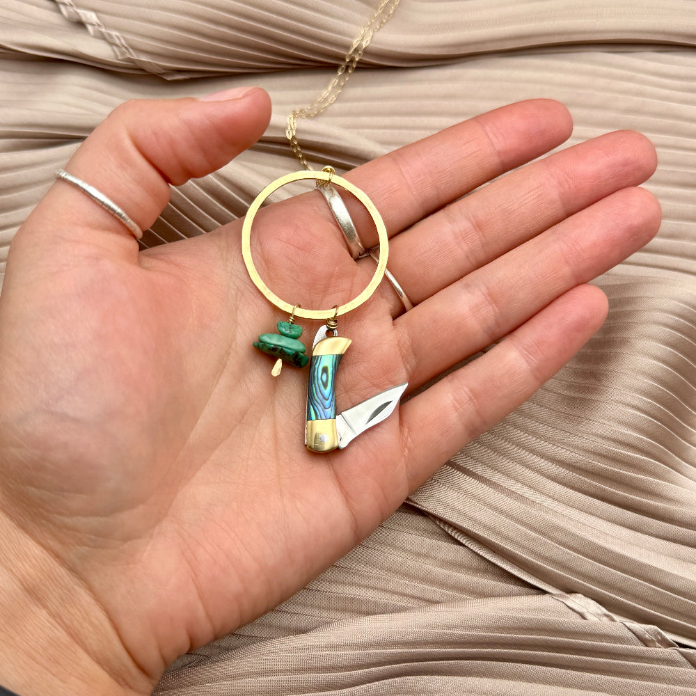 necklace with small abalone inlay pocketknife and two turquoise bead chips hanging from round open circle pendant 