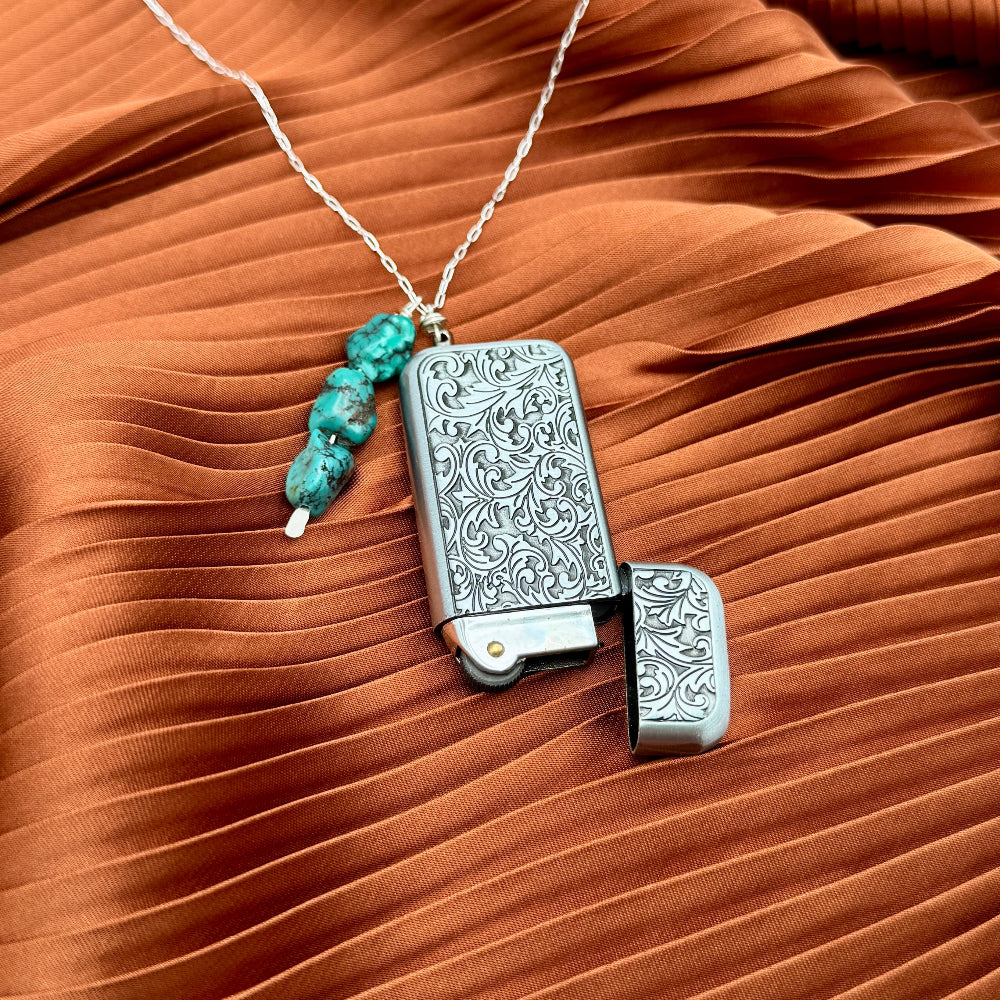 Silver engraved lighter with floral patterns, turquoise beads on a necklace chain