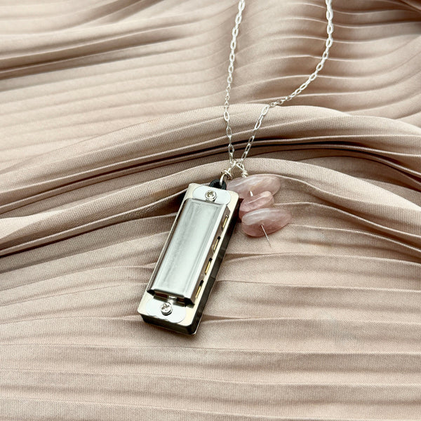 silver necklace with a tiny silver harmonica and three rose quartz nugget beads