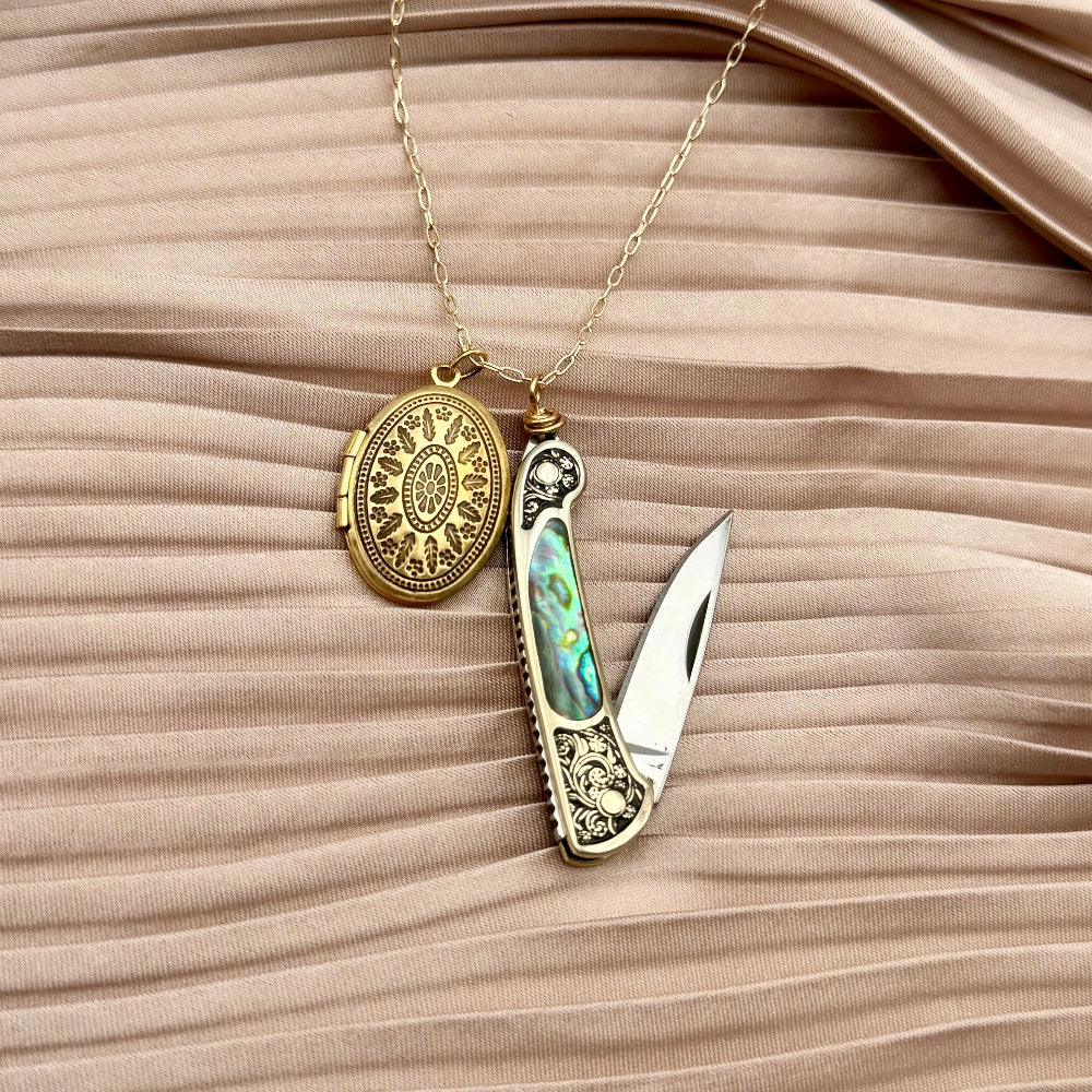 gold locket and a small ornate pocket knife with abalone inlay on chain, blending elegance and utility 