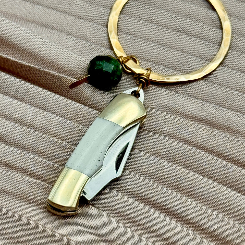 Necklace with miniature bone pocketknife and emerald bead hanging from round pendant