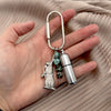 A hand holding a silver carabiner keychain with a rabbit shape charm, four turquoise beads, and a cylindrical lighter charm on a beige pleated background. 